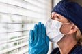 Prayerful Stressed Female Doctor or Nurse On Break At Window Wearing Medical Face Mask