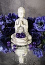 praying buddha statue with purple jelly beans and blue flowers Royalty Free Stock Photo