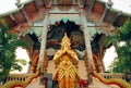 Praying Buddha statue standing at entrance of ancient Buddhist temple structure, Thailand Royalty Free Stock Photo