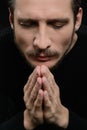 Praying with eyes closed. Devout bearded man praying and holding Royalty Free Stock Photo