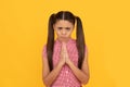 Praying girl child pray holding palms together in prayer gesture yellow background, plead