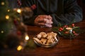 Praying hands of an elderly man on a table with Christmas cookies, burning candle and festive decoration, lonely holidays during Royalty Free Stock Photo