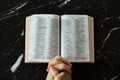 Praying hands folded in prayer to God Jesus Christ with open Holy Bible Book on dark granite background Royalty Free Stock Photo