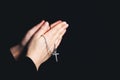 Praying hands holding a rosary, Closeup holding necklace with cross,pray for god in the dark, religious Christian symbol