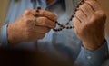 Praying hands of an old man holding rosary beads. Royalty Free Stock Photo