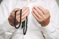 Praying hands of an old man holding rosary beads Royalty Free Stock Photo