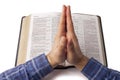 Praying hands over open bible