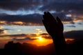 Praying hands on sunset background