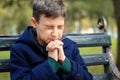 Praying little boy sitting on bench in park Royalty Free Stock Photo