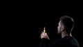 Praying man holding burning candle on dark background, spiritual ritual, faith Royalty Free Stock Photo