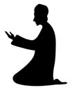 Praying man. Silhouette. A man in a Muslim long shirt and cap is kneeling and raising his palms up
