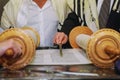 A praying man with a tefillin on his arm and head, holding a Torah, while reading a pray at a Jewish ritual Bar Mitzvah ceremony .
