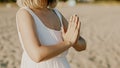 Praying meditating woman, reading mantras, directs thoughts, requests or gratitude to universe. Beach, morning near sea