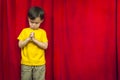 Praying Mixed Race Boy in Front of Red Curtain Royalty Free Stock Photo