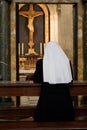 Praying nun in a temple of Vatican opposite the statue of Jesus Christ