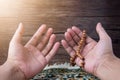 Muslim man hands praying and carrying prayer beads, on a prayer rug on a wooden background and in the sun