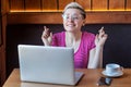 Praying! Portrait of wishful attractive young girl freelancer in pink t-shirt is sitting in cafe and working on laptop, closed