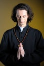 Praying priest with wooden cross