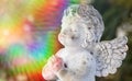 Praying stone angel with colorful sunbeam