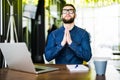 Praying for success. Front view of thoughtful young man holding hands on chin and looking up while sitting at his working place in Royalty Free Stock Photo