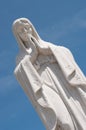 Praying Virgin Mary statue against a blue sky Royalty Free Stock Photo