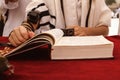 A praying young man hands with a tefillin holding a bible book, while reading a pray at a Jewish ritual