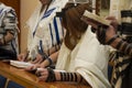 A praying young man with a tefillin on his arm and head, holding a bible book, while reading a pray at a Jewish ritual Royalty Free Stock Photo