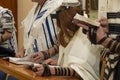 A praying young man with a tefillin on his arm and head, holding a bible book, while reading a pray Royalty Free Stock Photo