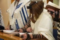 A praying young man with a tefillin on his arm and head, holding a bible book, while reading a pray at a Jewish ritual Royalty Free Stock Photo