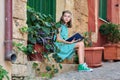 Pre-adolescent schoolgirl with a book sitting on steps of outdoor