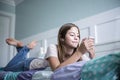 Pre-adolescent teen girl texting on a smartphone lying in bed at home