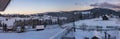 Pre-dawn alpine small quiet village and winter snowy mountains around panorama view. Part of the roof with icicles as a symbol of Royalty Free Stock Photo