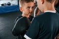 Pre fight preparing. Looking at each other. Young tattooed coach teaching the kids boxing techniques Royalty Free Stock Photo