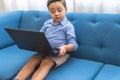 A pre-school child looks at a laptop monitor sitting on a sofa in his living room Royalty Free Stock Photo