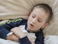 Pre-school sick boy in pyjama lying in bed with a digital thermometer in hand