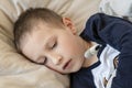 Pre-school sick boy in pyjama lying in bed with a digital thermometer