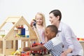 Pre-School Teacher And Pupils Playing With Wooden House