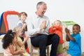 Pre School Teacher Reading Story To Children And Praying
