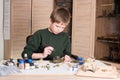 Pre teen boy assembling and painting plastic model tank at workplace in his room. Hobby concept.