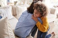 Pre-teen girl hugging her mother sitting on sofa in the living room, elevated, back view Royalty Free Stock Photo