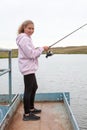 Pre-teen girl portrait with fish rod, female fisherman catching the fishes from pier Royalty Free Stock Photo