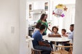 Pre teen girl sitting at the kitchen table with her three generation family celebrating her birthday, blowing out candles on her b Royalty Free Stock Photo