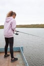 Pre-teen girl standing with fish rod, female fisherman catching the fishes from pier Royalty Free Stock Photo