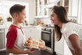 Pre-teen Hispanic boy presenting the cakes he has baked to his proud mother, close up Royalty Free Stock Photo