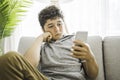 Pre-teen sit on the couch using smartphone and look sad and boring Royalty Free Stock Photo