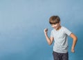 A pre-teen tween boy being silly on a colorful blue background with copy space