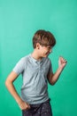 A pre-teen tween boy being silly on a colorful green background with copy space