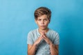 A pre-teen tween boy being silly with his hands in a praying or guru thinking mode on a colorful blue background with