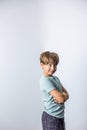 A pre-teen tween boy with his arms crossed with attitude standing near a corner with white walls with copy space