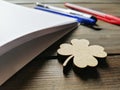 A pre-woven clover on a table next to the pens and notebook. Good luck for studying is four-leaf clover